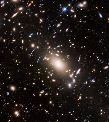 Abell S1063, a galaxy cluster, was observed by the NASA/ESA Hubble Space Telescope as part of the Frontier Fields programme. The huge mass of the cluster acts as a cosmic magnifying glass and enlarges even more distant galaxies, so they become bright enough for Hubble to see.